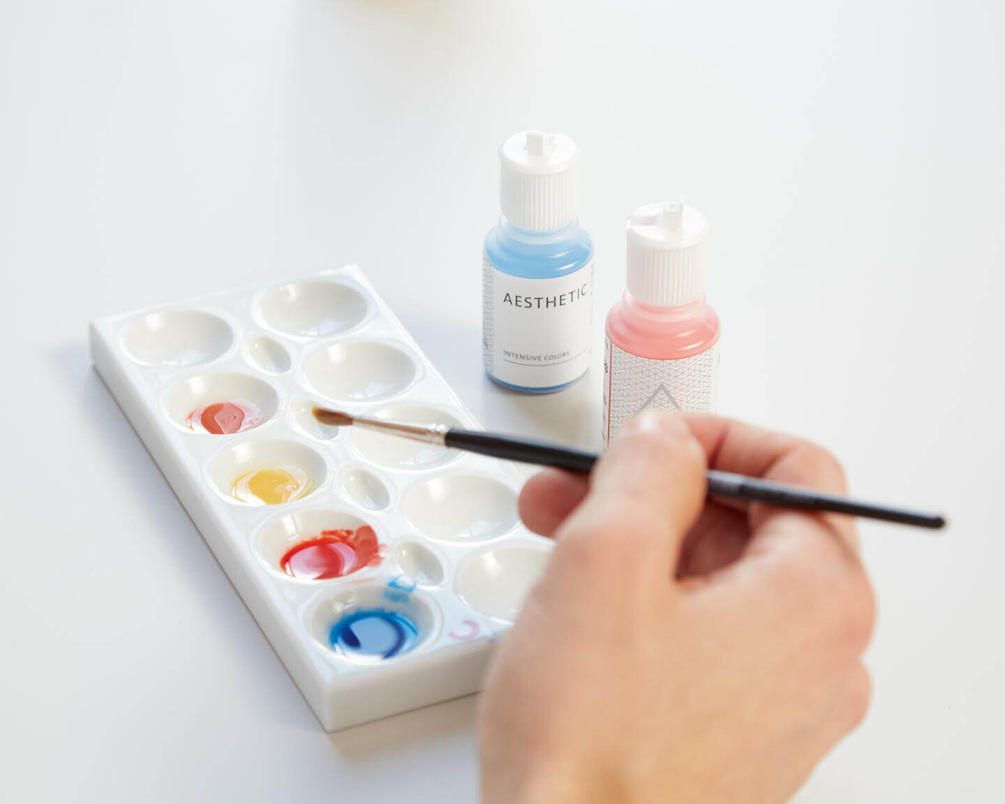 pensula tinuta in mana de un tehnician dentar ce utilizeaza lichide de individualizare a acrilatului candulor